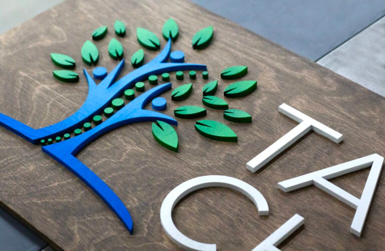 close-up of a personalized wood logo sign with custom chiropractic business logo. Aged walnut stain and custom color logo