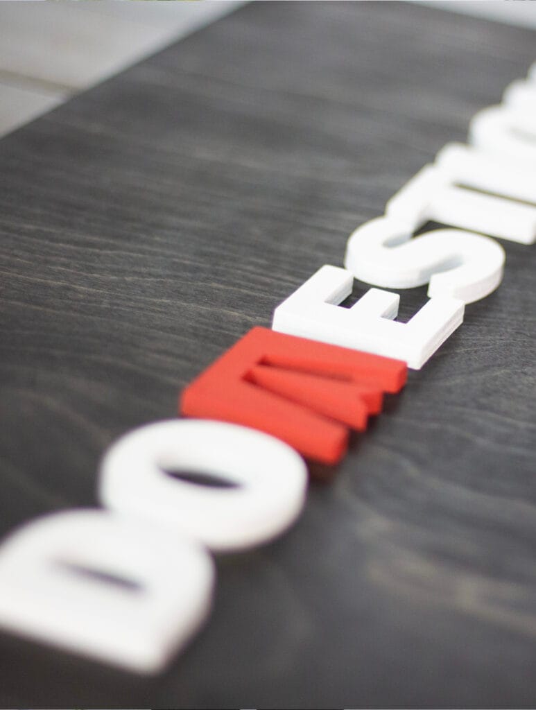 close-up of a black ebony stain sign with custom business logo made out of laser cut lettering. Red and white logo on a birch wood base.