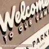 personalized welcome national park sign with family name on an aged walnut base with natural wood foreground