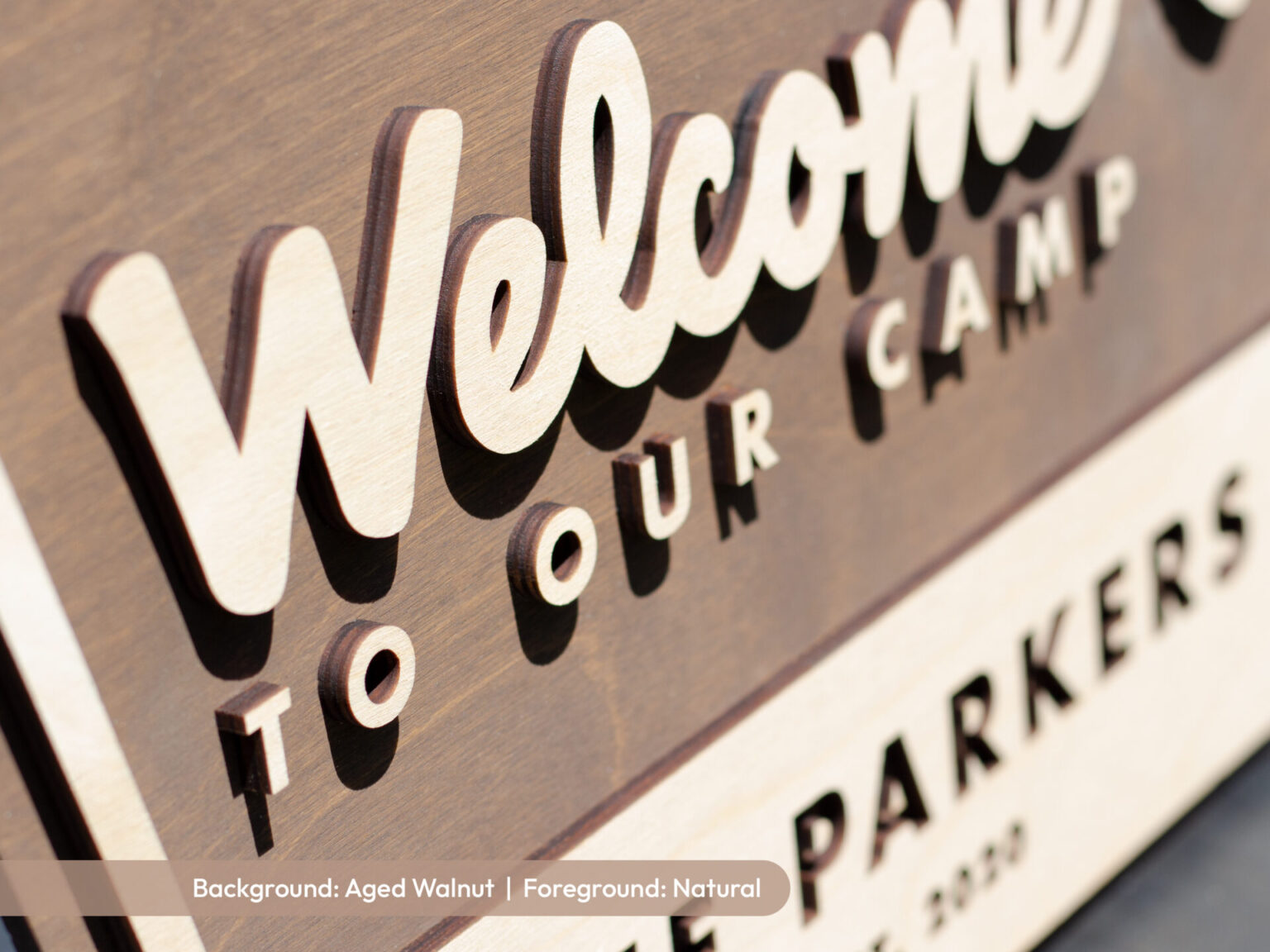 personalized welcome national park sign with family name on an aged walnut base with natural wood foreground