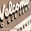 close up of birch national forest sign with welcome to our camp or welcome to our adventure laser cut lettering. Aged walnut stain behind a natural birch personalized wood sign