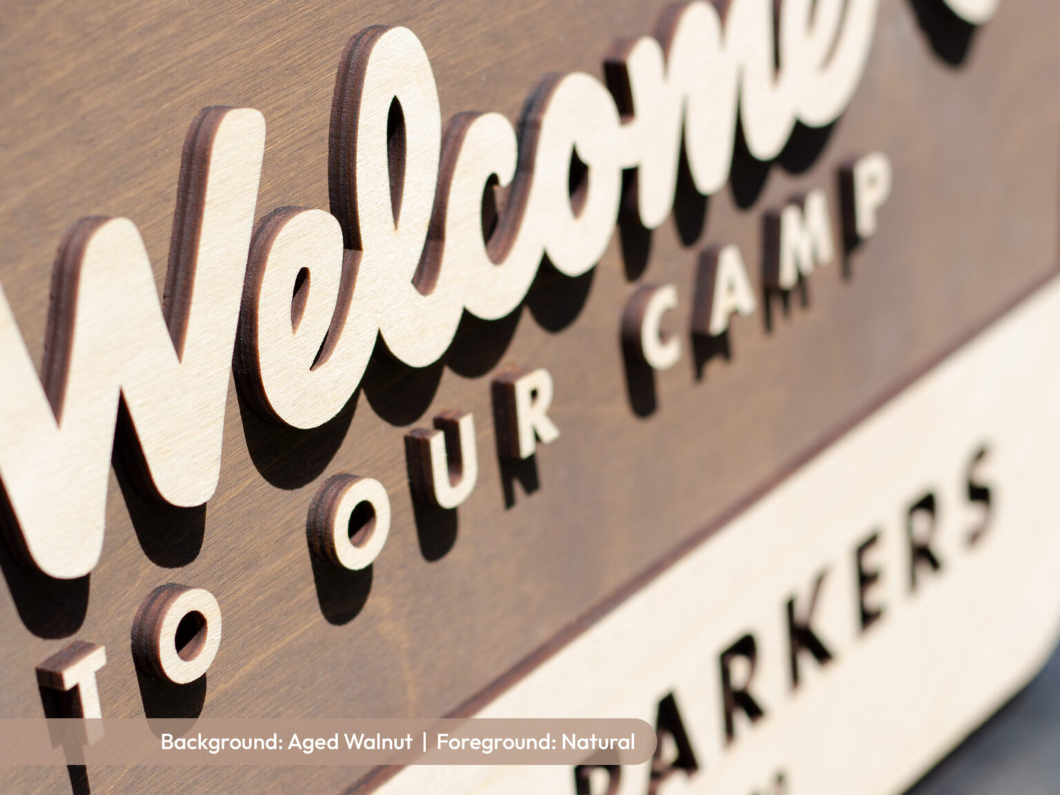 close up of birch national forest sign with welcome to our camp or welcome to our adventure laser cut lettering. Aged walnut stain behind a natural birch personalized wood sign