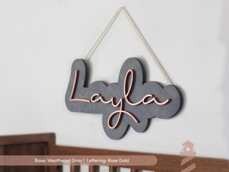 girl's custom laser cut wooden first name sign for bedrooms, nurseries, or playrooms. Weathered gray stain with rose gold lettering. Hung with a cotton rope.