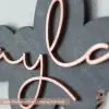 Elegant girl's laser cut wood bedroom nursery sign with grey base and rose gold lettering. Custom first name sign.