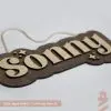kid's bedroom sign with aged walnut base and natural wood lettering. Hung with a cotton rope