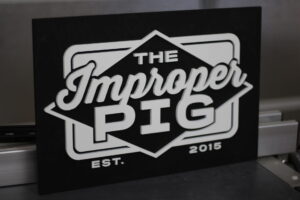 laser cut business sign with a white logo on an ebony wood base