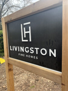 Exterior sign with black base and white lettering. Held up by a frame for exterior use