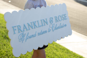 Custom laser cut logo wood sign on a white base with a contour-cut scalloped shape edge and a baby blue logo
