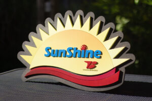 custom shape contour-cut wood aged walnut sign with a sunrise logo and company name engraved on the sign