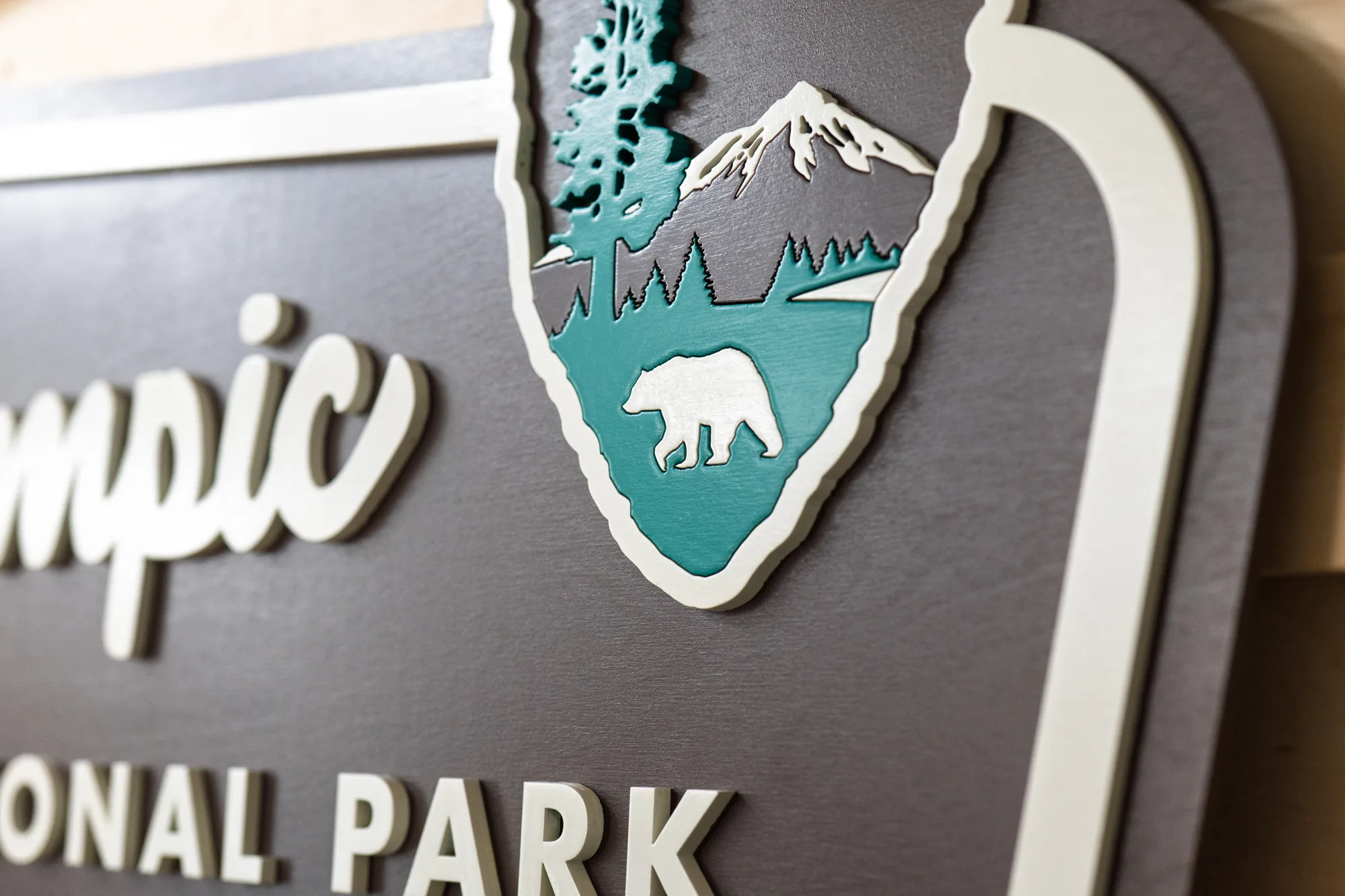 Close-up of the painted arrowhead emblem with a bear, pine tree and mountain