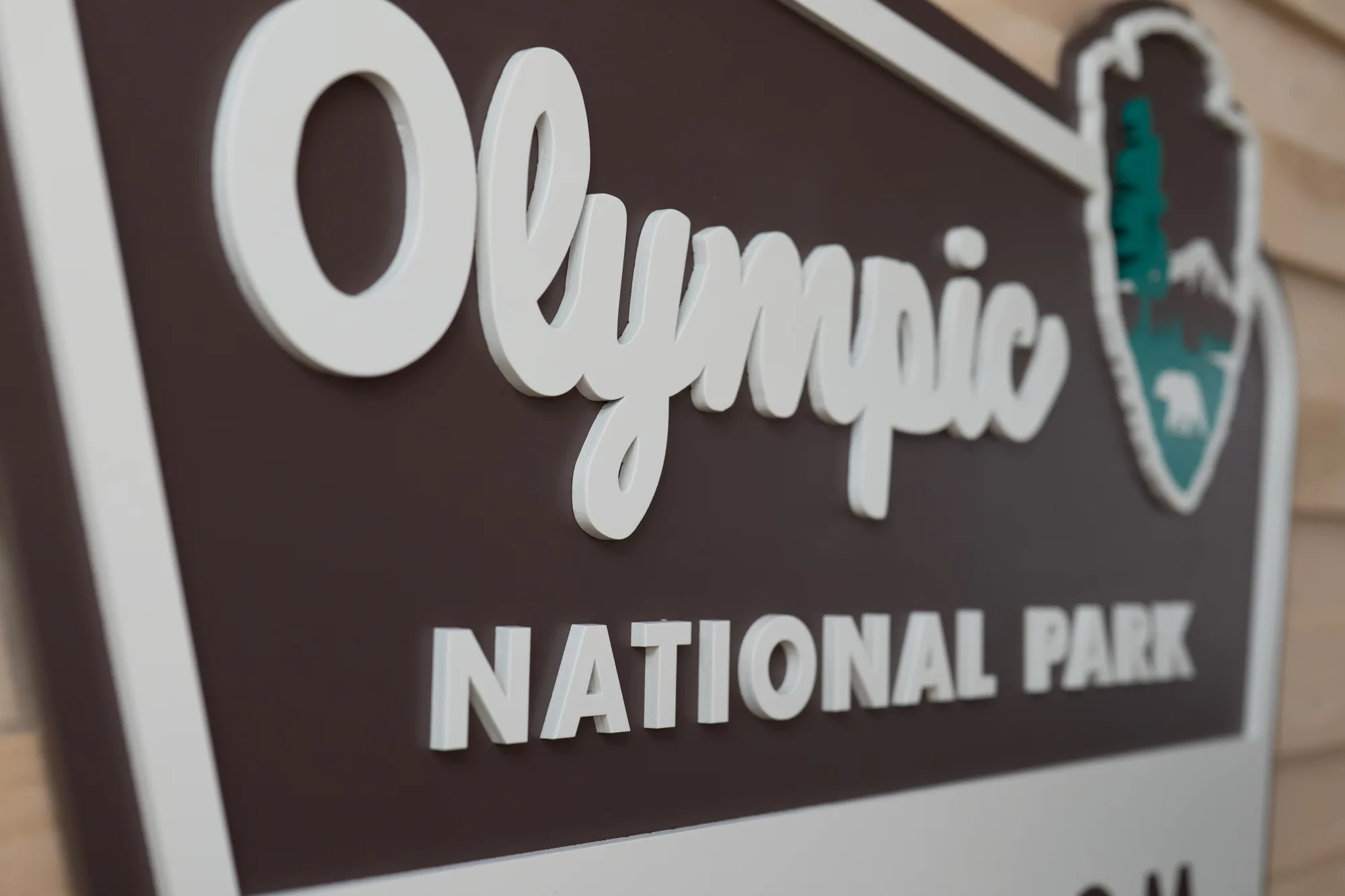 Raised cream lettering on a painted brown background, seen at an angle